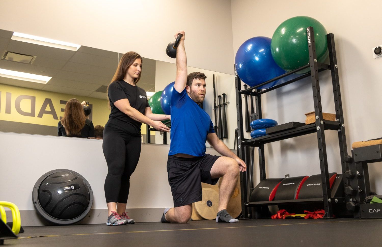 person exercising with weights in presence of a trainer