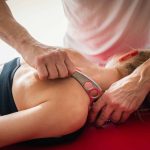 Physiotherapist performing IASTM treatment on a patient’s shoulder and upper back.